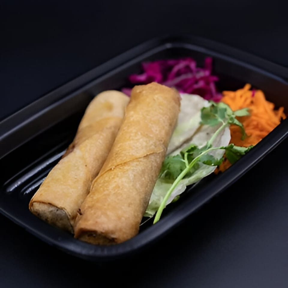 Two crispy Vietnamese spring rolls with shredded carrots, purple cabbage, and cilantro in a black container.
